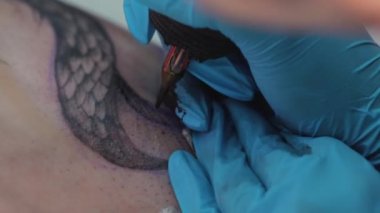 Tattoo artist filling tattoo using black ink - Tattoo making process in a salon. High quality 4k footage