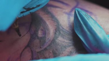 Tattoo master drawing tattoo on the client body using tattoo gun with black ink. High quality 4k footage