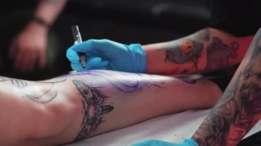 Freehand tattoo sketching in a tattoo parlour - Tattooing process in a studio. High quality 4k footage
