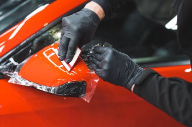 Adam arabanın yan aynasına şeffaf plastikten bir örtü koyup yakın çekim yapıyor. Yüksek kalite fotoğraf