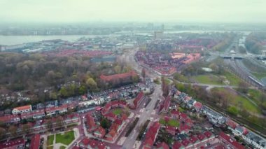 Arkasında yeşil benekler ve bir nehir olan güzel bir şehrin insansız hava aracı görüntüsü. Şehir ve doğa kavramı. Yüksek kalite 4k görüntü