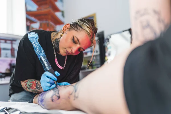 腿纹身的过程 女客户躺在纹身床上 观察她的女纹身艺术家在她的小腿上画了一个图案 高质量的照片 — 图库照片