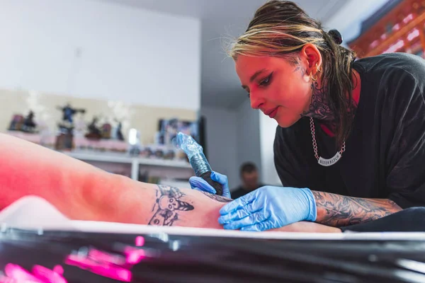 皮肤艺术 重点纹身艺术家在保护手套画纹身在客户的腿上 一个专业纹身工作室的内部 高质量的照片 — 图库照片