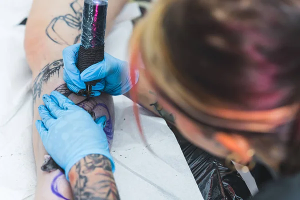 Сосредоточенная Женщина Татуировщица Делает Свою Татуировку Ноге Своих Клиентов Размытая — стоковое фото