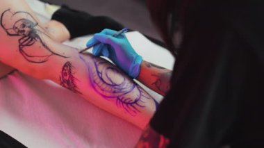 Dövme ustası, dövme stüdyosunda müşteri bacağı üzerine el yazısı dövmesi çiziyor. Yüksek kalite 4k görüntü