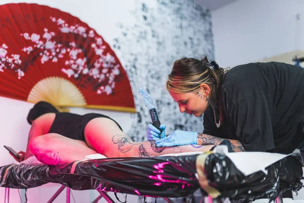艺术性纹身工作室内部 在当地女艺术家的纹身活动中 客人躺在她的腹部 腿纹身的概念 是的高质量的照片 — 图库照片