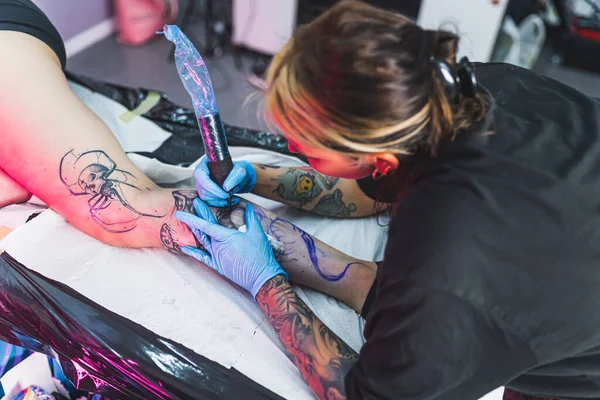 Sanat stüdyosunda beyaz bir müşterinin bacağına yeni bir dövme yaptırırken çekilmiş. Yüksek açılı iç manzara. Yüksek kalite fotoğraf