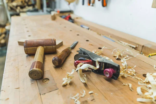 Carpenter tools - a wooden mallet, a chisel and a planer with wooden chips on the table. High quality photo