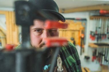 Marangoz bir bar kıskacına bakıyor, atölye geçmişi var. Yüksek kalite fotoğraf