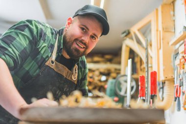 Masasında ahşap ve aletlerle çalışan gülümseyen beyaz bir marangoz. Yüksek kalite fotoğraf