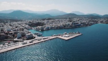 Yunanistan 'ın Girit adasındaki kıyı kenti Agios Nikolaos, deniz perspektifinden insansız hava aracıyla güneşli bir günde görüldü. Yüksek kalite 4k görüntü