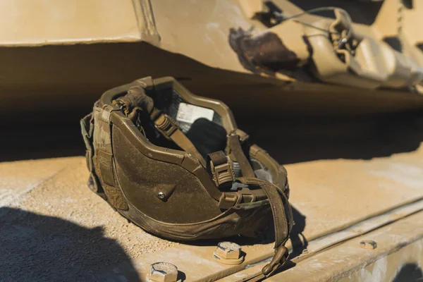 Dark-coloured military helmet lying upside down on a military US tank. Modern military equipment. High quality photo