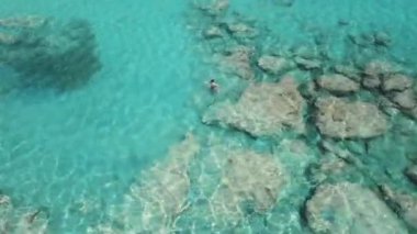 Gök mavisi bir kristal içinde Girit Denizi 'nin berrak sularında yüzen bir insan, yukarıdan insansız hava aracı görüşü. Yüksek kalite 4k görüntü