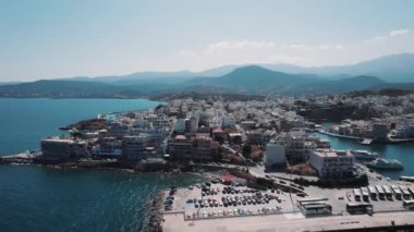 Yunan kıyı kenti Agios Nikolaos güneşli bir günde hava aracı perspektifinden görülüyor. Deniz kenarı. Yüksek kalite 4k görüntü