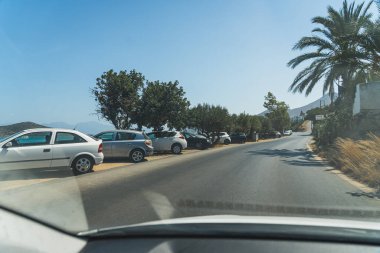 Agios Nikolaos, palmiye ağaçları ve göl manzaralı bir yolda duran arabalar. Yüksek kalite fotoğraf