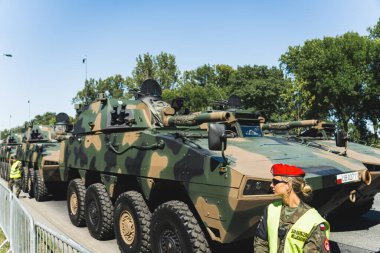 16.08.2023 Varşova, Polonya. Açık hava geçit töreninde kadın güvenliğin rehberliğinde caddede ilerleyen modern askeri tanklardan oluşan bir kolon. Yüksek kalite fotoğraf