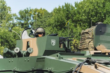 16.08.2023 Varşova, Polonya. Yükleyiciler bir askeri tankta yumurtadan çıkıyor. Kamuflaj boyalı tanktan gizlice bakan odaklanmış askerin açık hava portresi. Yüksek kalite fotoğraf