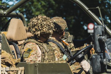 16.08.2023 Varşova, Polonya. Askeri araç kullanan ve kameraya bakmayan kamuflaj üniformalı ve kasklı iki silahlı askerin portresi. Yüksek kalite fotoğraf