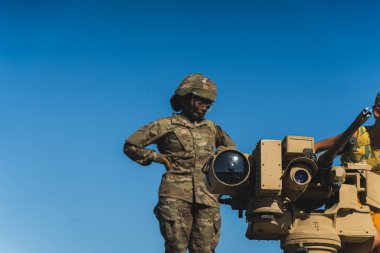 16.08.2023 Varşova, Polonya. Kamuflaj üniformalı siyah kadın asker arka planda parlak mavi gökyüzü olan tankın üzerinde duruyor. Uzayı kopyala Yüksek kalite fotoğraf