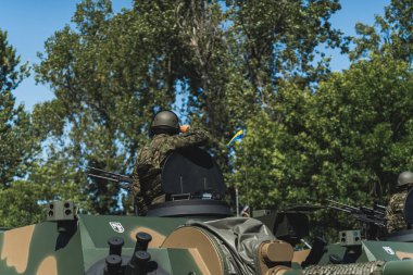 Tam donanımlı bir askerin tankın girişinden ağaçların arkasına baktığı arka plan. Askeri geçit töreni konsepti. Yüksek kalite fotoğraf