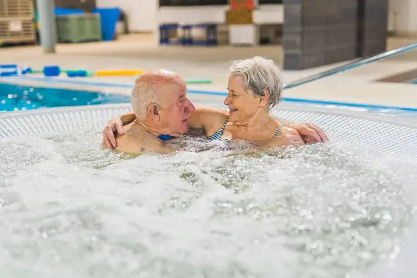 cute Caucasian senior couple enjoying the hot bubbly bath in the pool, old people concept. High quality photo