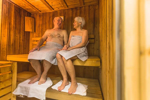full shot of a old lovely couple with grey towels having a great time in the sauna, old people concept. High quality photo