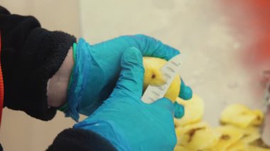 Mavi eldivenli, siyah lekeleri temizleyen ve patatesi keskin bir bıçakla temizleyen birinin yüksek açılı yakın çekimi. Yüksek kalite 4k görüntü