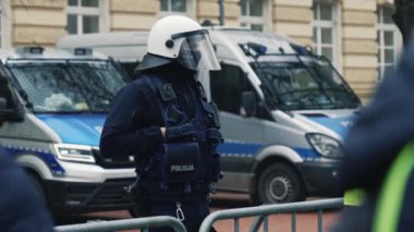 06.03.2024. Varşova, Polonya. Kasklı ve siyah üniformalı bir polis memuru gösteriye bakıyor. Yüksek kalite 4k görüntü