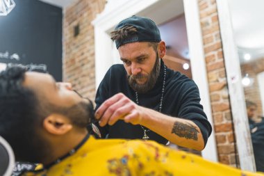 Modern bir berber dükkanında Hintli müşterisinin sakalını kesmeye odaklanmış. Yüksek kalite fotoğraf