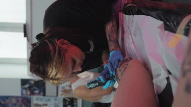 Kobieta Tatuażystka Rękawiczkach Robiąca Tatuaż Nodze Klienta Studio Tatuażu Pionowe — Wideo stockowe