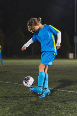 Gece futbol antrenmanı yapan açık mavi üniformalı genç bir kız. Yüksek kalite fotoğraf