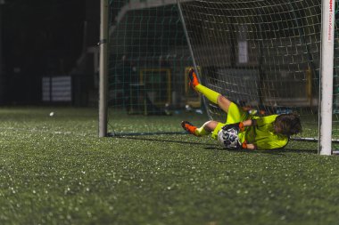 Sarı üniformalı bir kız kalecinin maçta elleri ile top yakalaması, kız futbol takımı. Yüksek kalite fotoğraf