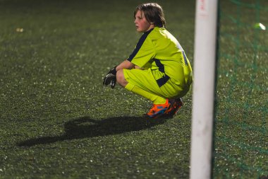 Genç bir kaleci kız kalenin önünde dinleniyor sarı üniformalı, okul futbol takımının önünde. Yüksek kalite fotoğraf