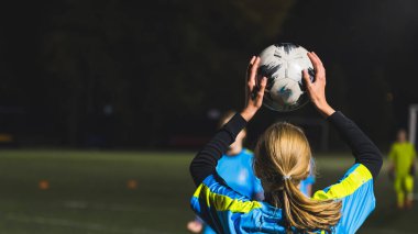 Futbol topu fırlatmaya hazırlanan, futbol oynayan sarışın bir kızın yakın çekim görüntüsü. Yüksek kalite fotoğraf