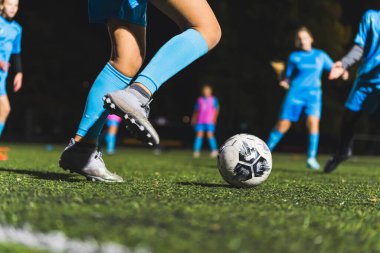 Mavi üniformalı kızların yeşil bir sahada futbol antrenmanı yaparken, kızların spor yaparken yakın çekimleri. Yüksek kalite fotoğraf