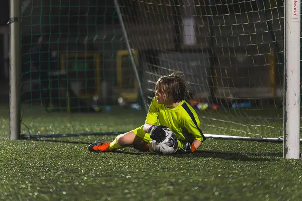little goalkeeper girl catching a soccer ball in the goal-net, teenage sportive life. High quality photo