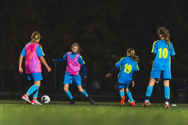 teenage Caucasian girls playing football at the late evening practice, full shot, teenage lifestyle. High quality photo