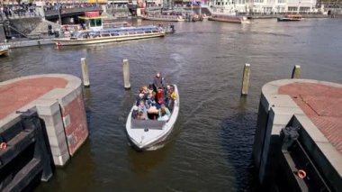 Turistler, güneşli bir günde Amsterdam Kanalı 'nda bir yolcu teknesiyle seyahat ediyorlar. Yüksek kalite 4k görüntü