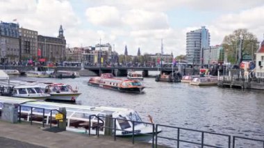 12.03.2024. Amsterdam merkez tren istasyonunun önündeki kanal gezisi teknesi, şehir manzaralı. Yüksek kalite 4k görüntü