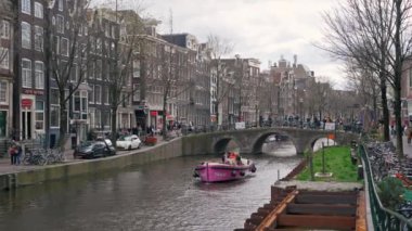 Hollanda 'nın bulutlu bir gününde Amsterdam kanallarında gezinen bir tekne. Yüksek kalite 4k görüntü