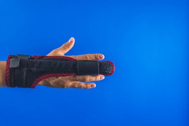 Mavi arka planda orta parmağında bir sabitleme tahtası var. Yüksek kalite fotoğraf