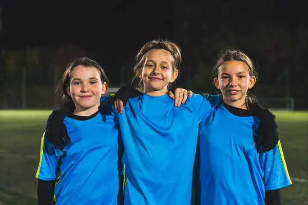 medium shot of three young girls in football blue sportswear taking a photo together. High quality photo