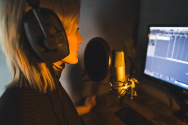 Bir radyo istasyonunda sunucu olarak çalışan genç bir kadın, orta ölçekli bir görüntü, podcast stüdyosu. Yüksek kalite fotoğraf