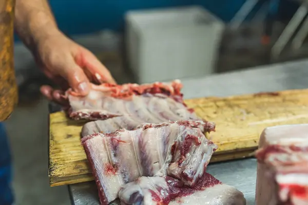 a butcher cutting pig ribs on the wood, slaughterhouse, preparing meat for sale. High quality photo