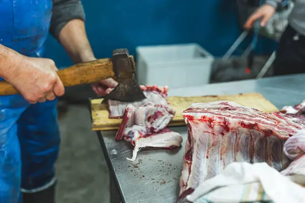 a man cutting the ribs of a pig with an axe at the slaughterhouse, food industry. High quality photo