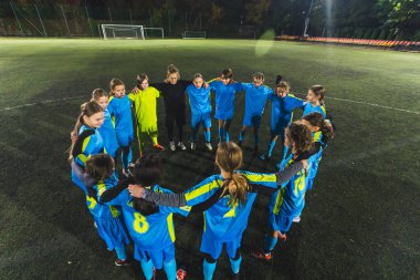 Genç liseli kızlar ve bayan antrenörleri antrenman, futbol ve takım çalışmasına başlamadan önce birbirlerine sokuluyorlar. Yüksek kalite fotoğraf