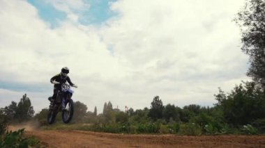 Genç adam toprak motosiklet sürme alıştırması yapıyor. Kum sıçrıyor. Yüksek kalite 4k görüntü