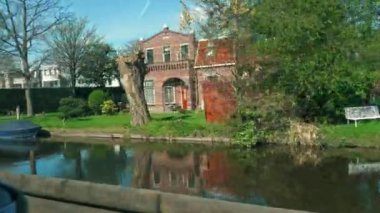 Amsterdam yakınlarındaki bir kanalda araba kullanmak, kenardaki evler, güzel manzaralar. Yüksek kalite 4k görüntü