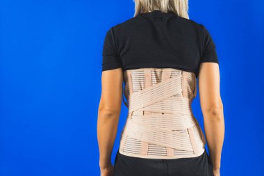 Mavi arka planda izole edilmiş insan vücudunda bel desteği. Sırt travması. Sırt desteği, ortopedik bel, sırt kasları için destek kemeri. Belden aşağısı ağrıyor. Yüksek kalite fotoğraf