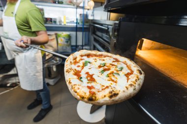 Fırından pizza çıkarıyorum. Yemek, İtalyan mutfağı ve yemek pişirme konsepti. Pizza fırınını pizzacıdan soymak. Yüksek kalite fotoğraf